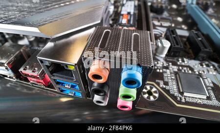Carte mère moderne. Connecteurs audio de couleur, USB ou LAN femelles, refroidisseur en aluminium pour chipset, puce sur carte de circuit imprimé noire. Détail artistique. Banque D'Images