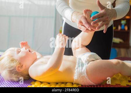 Maman donne au bébé un massage des pieds avec des boules de massage. Gros plan Banque D'Images