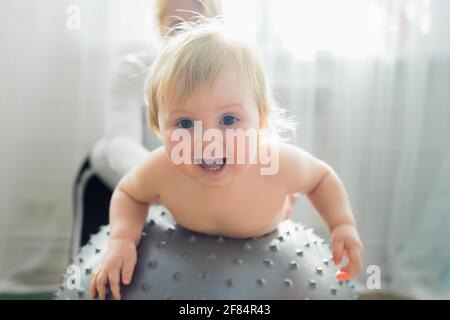 Maman est engagée dans la gymnastique avec le bébé sur un ballon gonflable. Fitball, gymnastique pour un enfant. Banque D'Images