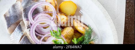 Plateau de fruits de mer avec tranche de maquereau fumé, pommes de terre frites, tranches de filet de poisson, décoré d'oignons Banque D'Images