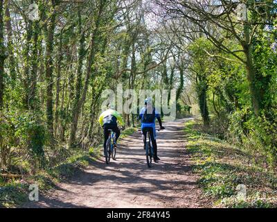 Deux cyclistes adultes sur une route de vélo de campagne sur Wirral, dans le nord-ouest de l'Angleterre. Le chemin fait partie de la route 56 du réseau national du cycle du Royaume-Uni. Banque D'Images