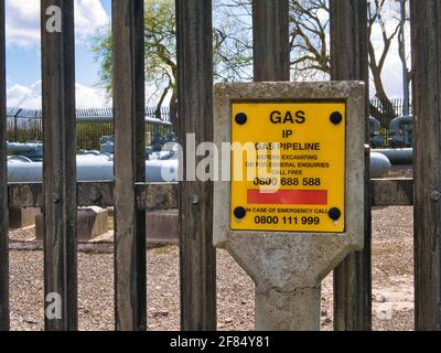 Un panneau jaune indiquant un pipeline de gaz à pression intermédiaire (IP) au niveau d'une installation au-dessus du sol (AGI) au Royaume-Uni. Banque D'Images