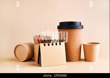 maquette de marque avec beaucoup de papier artisanal et différents sujets, verre pour café. Bureau avec bloc-notes en papier et boîte de crayons. Espace de travail contemporain pour homme, style minimaliste. Maquette. Banque D'Images