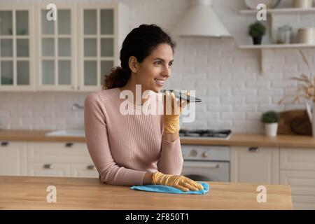 Une jeune femme au foyer latirait la cuisine dicte son message au téléphone Banque D'Images