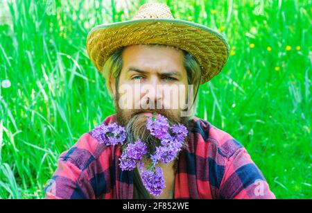 Bel homme barbu avec des fleurs dans la barbe. Homme avec une barbe décorée. Banque D'Images