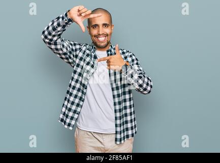 Hispanique adulte homme portant des vêtements décontractés souriant faisant cadre avec les mains et les doigts avec le visage heureux. Créativité et concept de photographie. Banque D'Images