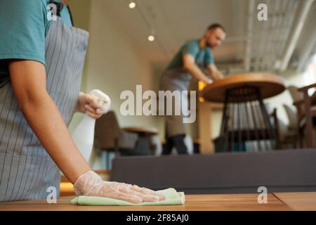 Gros plan de la table de nettoyage de serveuse féminine non reconnaissable dans le café avec des touches de bois chaudes, un espace de copie Banque D'Images