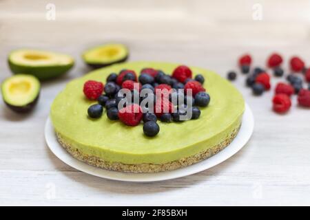 Délicieux gâteau cru à l'avocat et au citron vert maison avec myrtilles et framboises, recettes végétaliennes saines Banque D'Images