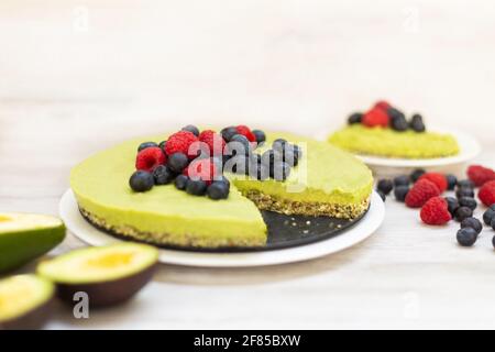 Délicieux gâteau cru à l'avocat et au citron vert maison avec myrtilles et framboises, recettes végétaliennes saines Banque D'Images