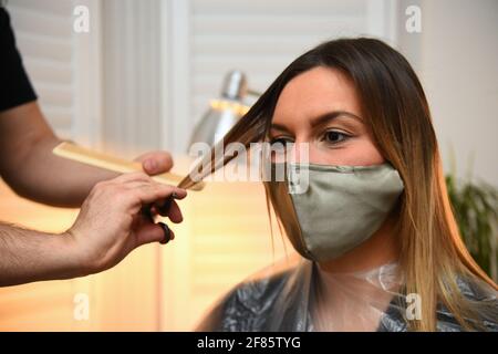 Secret Spa coiffeur NAS Ganev coupe les cheveux d'Amy Pallister, 27 ans, juste après minuit chez elle à Balham, dans le sud de Londres. Cinq femmes de ménage désespérées pour une garniture et un bronzage ont réservé NAS Ganev, styliste de Secret Spa, et l'artiste de bronzage Magdelaine Gibson pour visiter leur maison à une minute après minuit pour des coupes de cheveux et une peau bronzée alors que les restrictions du coronavirus se sont atténuées dans toute l'Angleterre. Le Secret Spa, qui offre des services de beauté et de bien-être à la maison à Londres, Manchester et Brighton, a prolongé ses heures d'ouverture pour accueillir 350 soins de beauté le premier jour de levée de restrictions, avec le premier appoi Banque D'Images