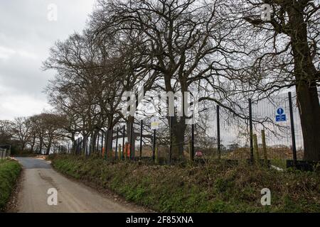 Great Missenden, Royaume-Uni. 9 avril 2021. Les agents de sécurité HS2 gardent une zone clôturée sur Leather Lane où plusieurs chênes centenaires ont été abattus pour permettre la construction d'une route d'accès temporaire et d'un composé pour la liaison ferroviaire à grande vitesse HS2. Suite à la pression des résidents locaux (plus de 40,000 personnes ont signé une pétition pour sauver les arbres), du Conseil de Buckinghamshire et du Chilterns conservation Board, il semble que les plans de HS2 ont été modifiés de manière à préserver certains des arbres le long de la voie de campagne ancienne riche en faune. Crédit : Mark Kerrison/Alamy Live News Banque D'Images