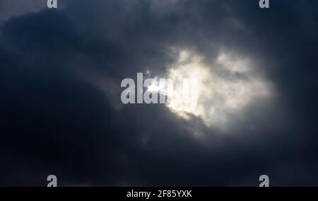 Une poignée de rayons du soleil se battent à travers des nuages d'orage envoûtant et sombre. Banque D'Images