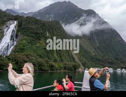 Bateau touristique sur Milford Sound, Nouvelle-Zélande, 28 mars 2021 - les touristes prennent des photos de Milford Sound dans la région Fiordland de la région sud-ouest de la Nouvelle-Zélande. À gauche, les chutes Lady Elizabeth Bowen, à 162 mètres, sont les plus hautes chutes du fjord et trois fois la hauteur des chutes Niagara. Crédit : Rob Taggart/Alamy Banque D'Images