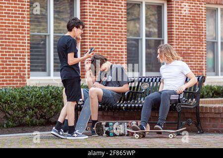 Frederick, MD, USA 04-07-2021: Trois adolescents portant des vêtements décontractés tendance sont suspendus dans un parc de la ville par une journée ensoleillée. Image de concept pour le gène Banque D'Images