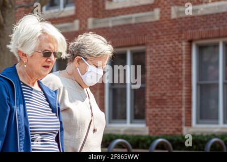 Frederick, Maryland États-Unis 04-07-2021: Deux femmes caucasiennes âgées marchent à l'extérieur lors d'une journée ensoleillée pendant la pandémie de COVID 19. On porte un masque facial bu Banque D'Images