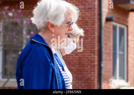 Frederick, Maryland États-Unis 04-07-2021: Deux femmes caucasiennes âgées marchent à l'extérieur lors d'une journée ensoleillée pendant la pandémie de COVID 19. On porte un masque facial bu Banque D'Images
