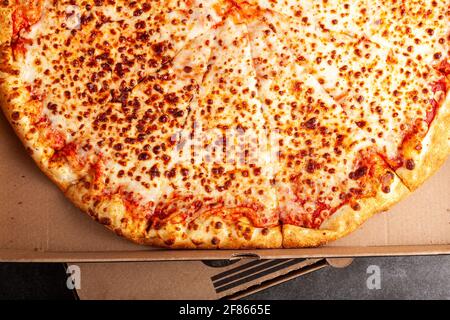 Image de plat d'un magasin de four frais acheté de pizza tranché à quatre fromages dans une boîte à pizza en carton. Il a une riche garniture offrant un délicieux en-cas. Foo rapide Banque D'Images