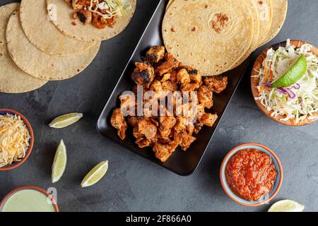 Image en gros plan d'un plat mexicain de tacos avec des tortillas de maïs, morceaux de poulet précuits, précuits, limaces de chou, fromage râpé, sauce salsa et crème Banque D'Images