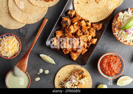 Image en gros plan d'un plat mexicain de tacos avec des tortillas de maïs, morceaux de poulet précuits, précuits, limaces de chou, fromage râpé, sauce salsa et crème Banque D'Images