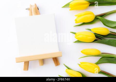 Pose à plat avec fleurs de tulipe jaunes et cadre photo vide sur fond blanc. Carte de vœux pour Pâques, Fête des mères, Journée internationale de la femme Banque D'Images