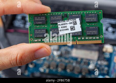 Image rapprochée isolée montrant un technicien informatique ou un consommateur tenant une carte RAM en main avec un intérieur d'ordinateur portable ouvert vu en arrière-plan. Concept i Banque D'Images