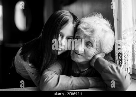 Une petite fille embrasse sa vieille grand-mère. Photo en noir et blanc. Banque D'Images