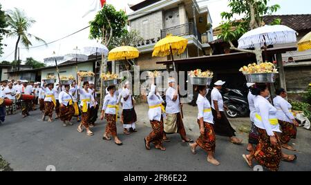 Procession de femmes habillées traditionnellement portant des offrandes de temple / gebogans sur leur tête près d'Ubud, Bali, Indonésie. Banque D'Images