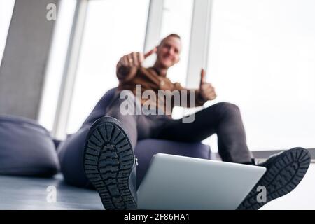 Un pied d'homme à chaussures se trouve à proximité de l'ordinateur portable. L'homme veut monter sur son ordinateur portable Banque D'Images