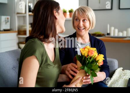 La mère surprise reçoit un bouquet de fleurs de la fille adulte Banque D'Images
