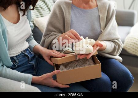 Femme donnant boîte cadeau avec chaussons bébé en tricot Banque D'Images