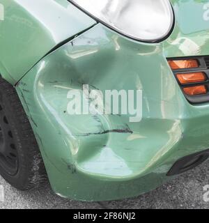 Voiture verte bosselée. La carrosserie latérale de la voiture a été endommagée par un accident dans la circulation. Gros plan. Banque D'Images