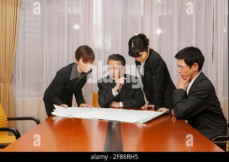 Les professionnels examinent les plans dans la salle de conférence du bureau Banque D'Images