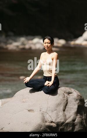 Portrait belle jeune femme méditant dans lotus pose sur le soleil rock Banque D'Images