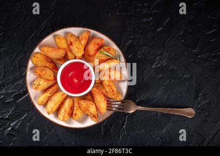 Quartiers de pommes de terre cuits sur noir avec espace de copie Banque D'Images