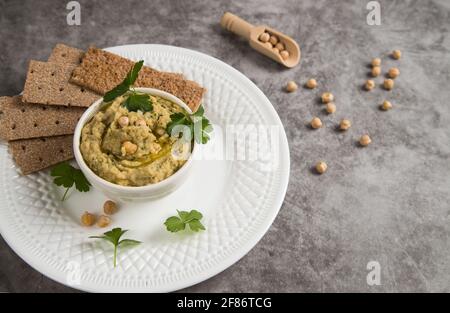 Pâte de pois turcs houmous de pois chiches dans une assiette sur fond gris. Banque D'Images