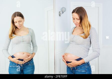 Femme enceinte de 9 mois et réflexion dans un miroir Banque D'Images