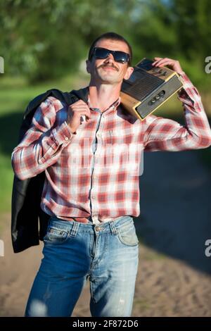 Drôle d'homme habillé dans le style des années 90 avec un magnétophone de cassette. Banque D'Images