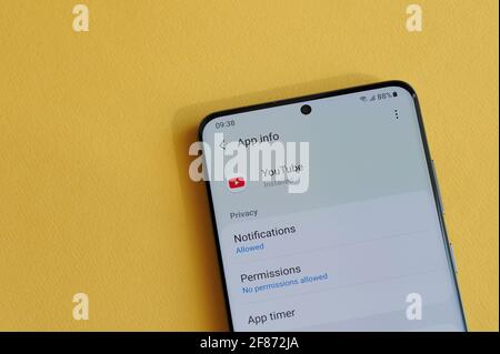 New york, Etats-Unis - 12 avril 2021 : modification des paramètres de confidentialité dans l'application youtube sur l'écran du smartphone sur fond jaune Banque D'Images