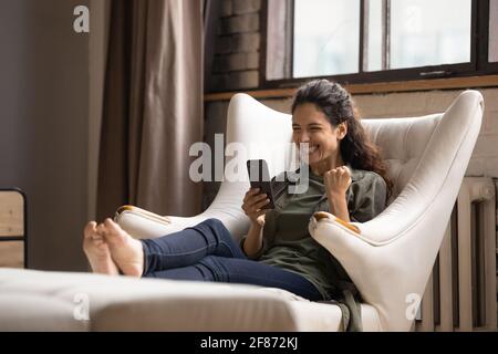 Une femme surjoyée regardant l'écran du téléphone, a reçu de bonnes nouvelles, se réjouissant Banque D'Images