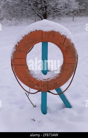 Une bouée de sauvetage ou une ceinture de sauvetage dans la neige au bord de la rivière hiver Banque D'Images