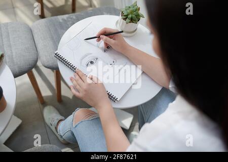 Image en gros plan du visage d'un étudiant en art talentueux dans un carnet d'esquisses à l'encre noire Banque D'Images