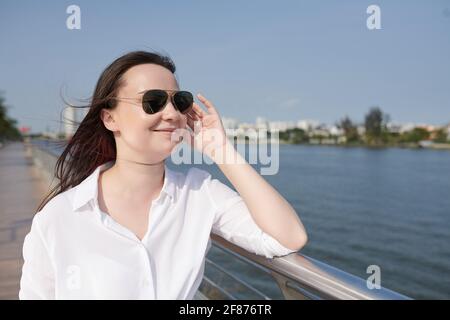 Jeune femme souriante et attirante marchant sur l'embarquements de la rivière et regardant à l'eau Banque D'Images