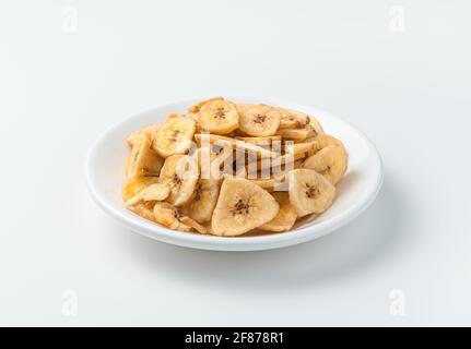 Bananes séchées dans une assiette blanche sur fond clair. Vue latérale, gros plan. Banque D'Images