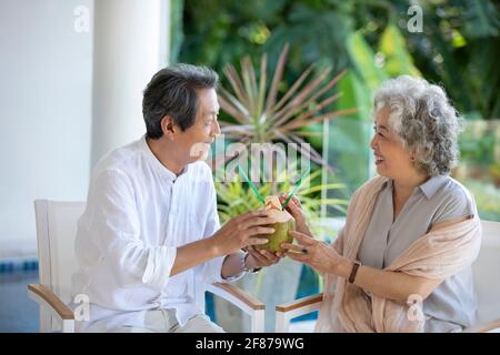 Bon couple senior qui boit du lait de coco sur le balcon Banque D'Images