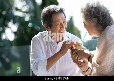 Bon couple senior qui boit du lait de coco sur le balcon Banque D'Images