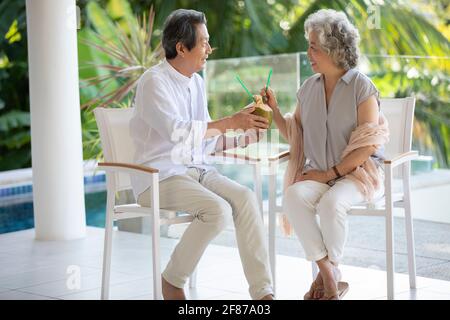 Bon couple senior qui boit du lait de coco sur le balcon Banque D'Images