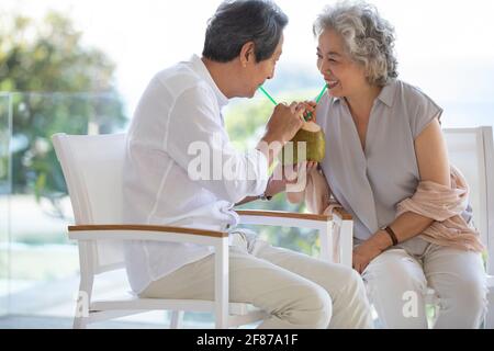 Bon couple senior qui boit du lait de coco sur le balcon Banque D'Images