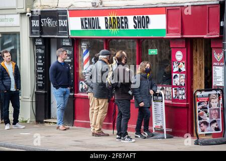 Chichester, Royaume-Uni. 12 avril 2021. Les hommes font la queue à l'extérieur d'un barbier, car la vente au détail n'est pas essentielle et d'autres entreprises rouvrent à mesure que les restrictions de verrouillage de l'Angleterre sont assouplies. Crédit : Paul Terry photo/Alamy Live News Banque D'Images