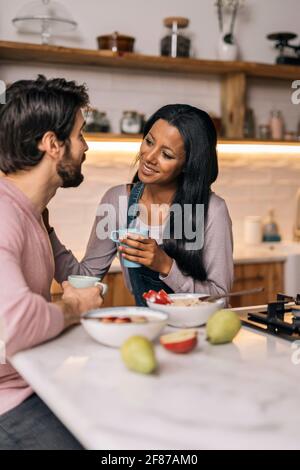 Femme noire smiley et son petit-ami ayant un délicieux petit-déjeuner dans la cuisine à la maison. Banque D'Images