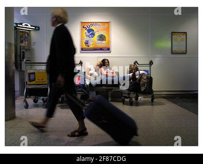 PASSAGERS RETARDÉS À L'AÉROPORT DE GATWICK JUILLET 2001 L'ÉTÉ COMMENCE ICI une publicité sur le mur de Gatwick. Les passagers attendent, se précipitent, se reposent sur la file d'attente, etc. Tous les éléments de l'existence quotidienne des gatewicks, à l'avance sont les vacances d'été et encore plus de retards et d'annulations prévus pour le public voyageur. Banque D'Images